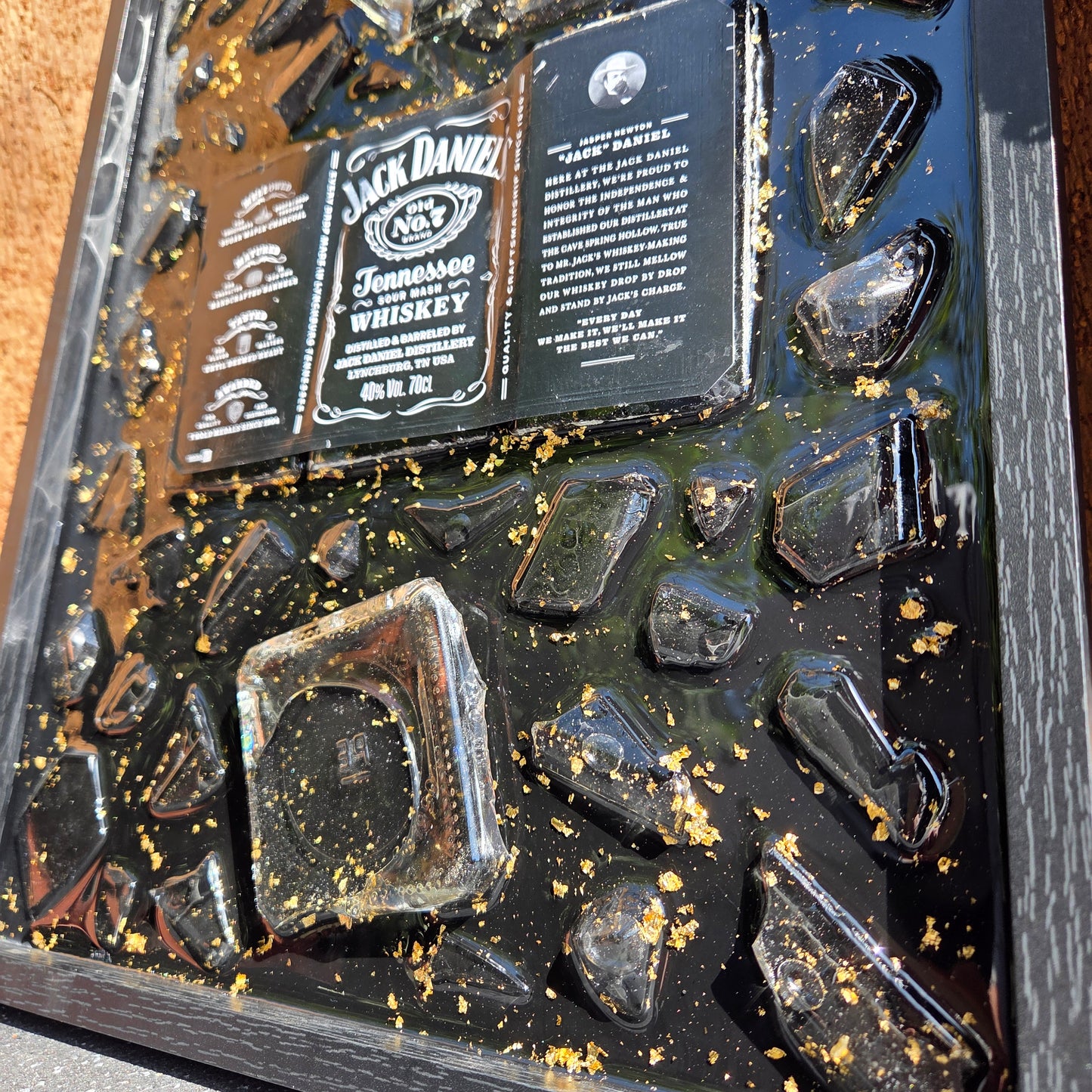 Tableau décoratif artisanal Jack Daniel’s avec bouteille et éclats de verre vert coulés dans la résine époxy avec feuilles d'or, cadre noir élégant, création unique faite main