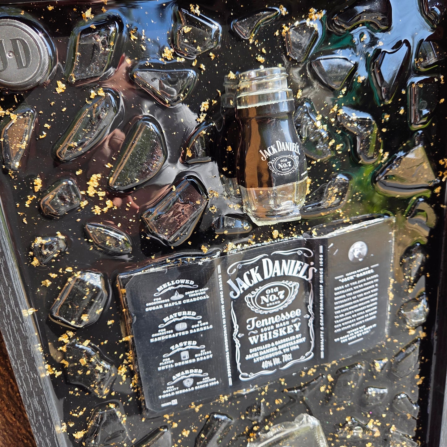 Tableau décoratif artisanal Jack Daniel’s avec bouteille et éclats de verre vert coulés dans la résine époxy avec feuilles d'or, cadre noir élégant, création unique faite main