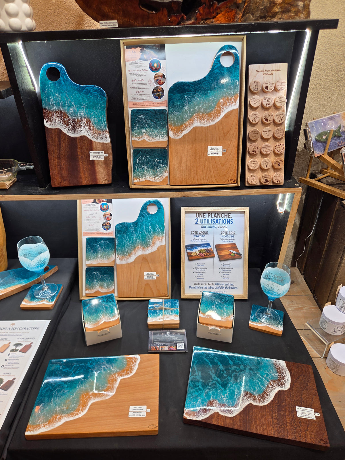 Présentation complète de l'univers vague C Bo sur un stand : planches, verres, coffrets et sous-verres en résine époxy